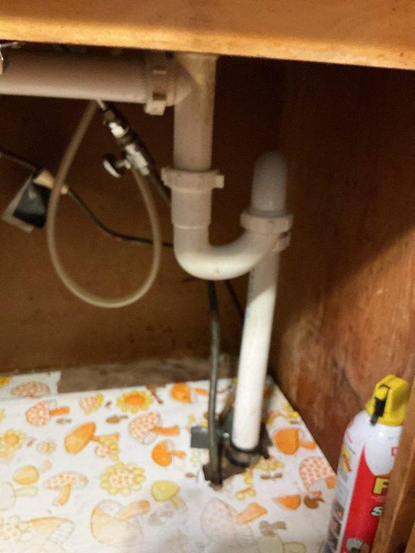 Successfully cleared severe clog in 135-year-old kitchen double sink drain system by dismantling the P-trap and removing accumulated debris. Inspected PVC plumbing configuration under sink for proper drainage function and reassembled all components, confirming complete water flow restoration with no leaks.