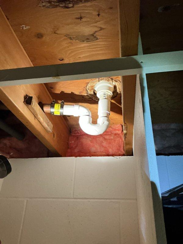 Resolved clogged shower drain by diagnosing and replacing damaged P-trap. Identified significant water damage and mold growth in the surrounding wooden enclosure where moisture had been leaking through pipe penetration. Installed new trap assembly to restore proper drainage functionality.