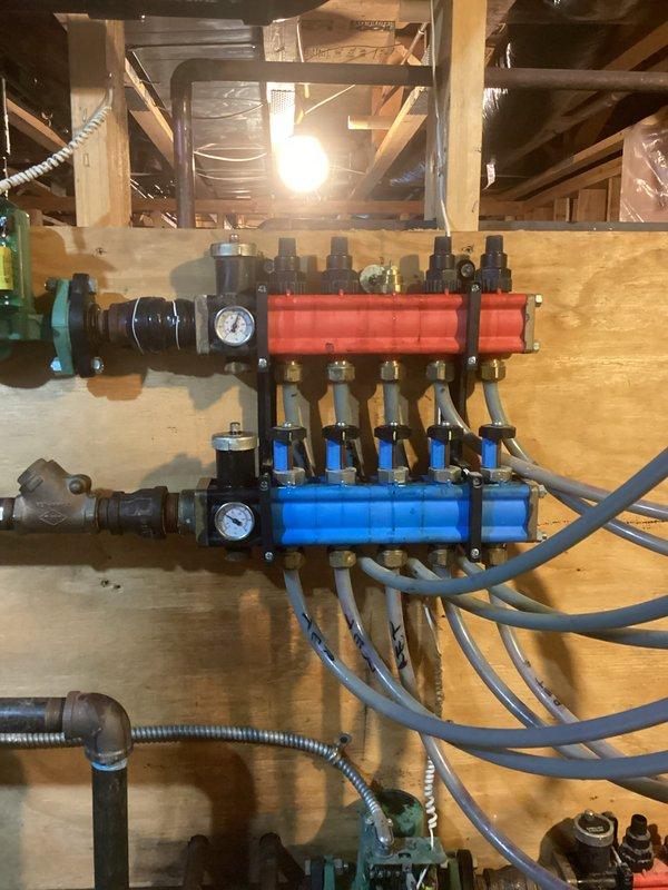 Inspected garage boiler system with non-functioning loops. Found only 2 of 5 loops circulating properly due to severely plugged manifolds with degraded plastic plungers. Disassembled manifold to assess damage. Recommended complete replacement of manifolds, installation of magnetic filter, and comprehensive system flush to prevent future blockages and restore proper circulation to all heating zones.