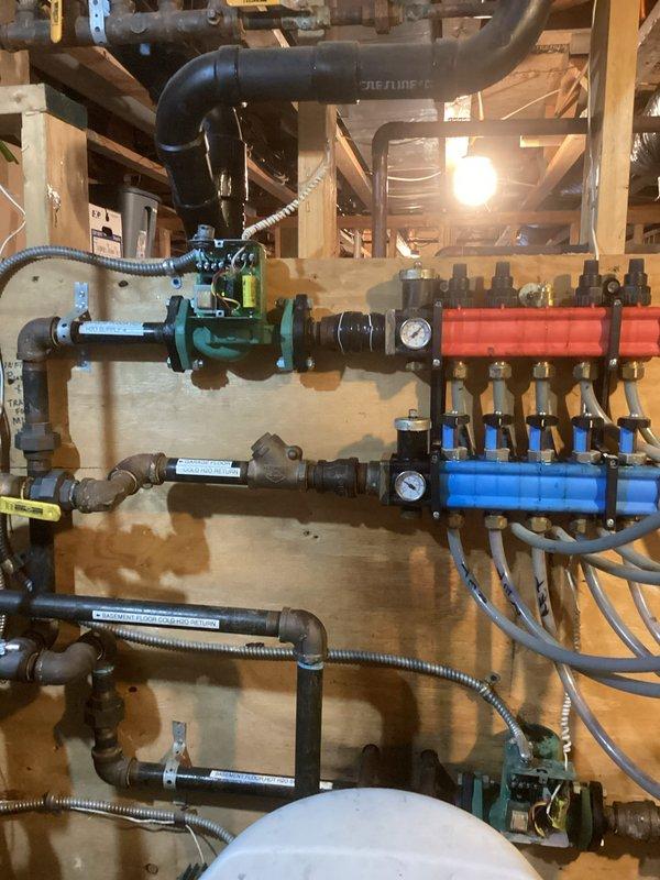 Inspected garage boiler system with non-functioning loops. Found only 2 of 5 loops circulating properly due to severely plugged manifolds with degraded plastic plungers. Disassembled manifold to assess damage. Recommended complete replacement of manifolds, installation of magnetic filter, and comprehensive system flush to prevent future blockages and restore proper circulation to all heating zones.