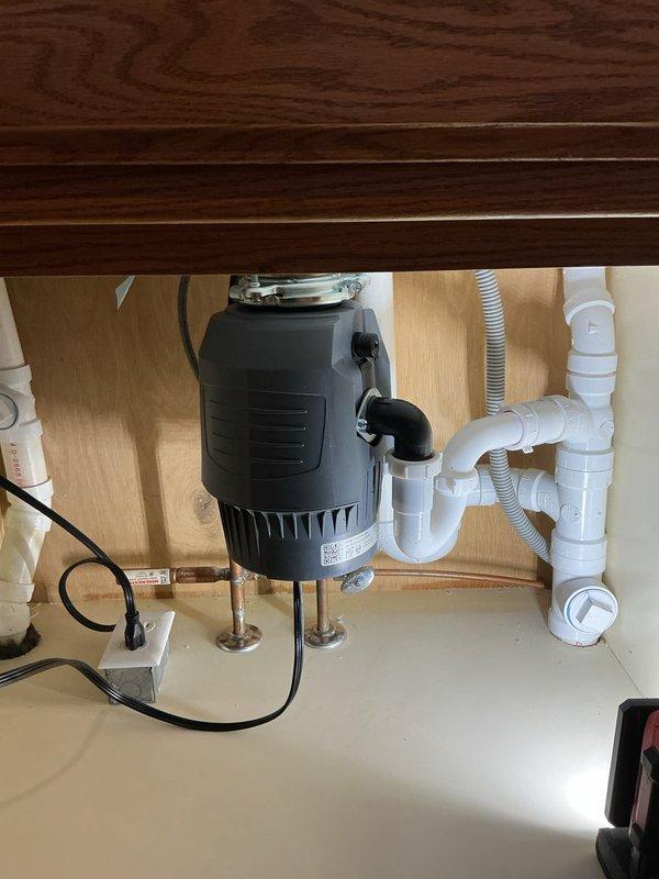 Successfully reinstalled kitchen sink plumbing following countertop replacement, including new faucet installation, InSinkErator garbage disposal installation, and reconfiguration of drain lines with PVC piping to ensure proper drainage.