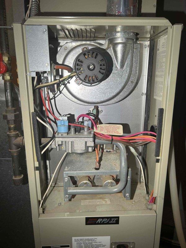 Performed comprehensive furnace tune-up on 30-year-old RPI II system with intermittent operation issues. Adjusted gas train pressure from 3.94 inWC to 3.34 inWC and cleared accumulated debris from condensate drain line and trap. Verified proper function of inducer motor, capacitor, pressure switch, control board connections, and thermostat operation with combustion CO recorded at 2 ppm. Noted moderate condition of return air filter; system now operating normally.