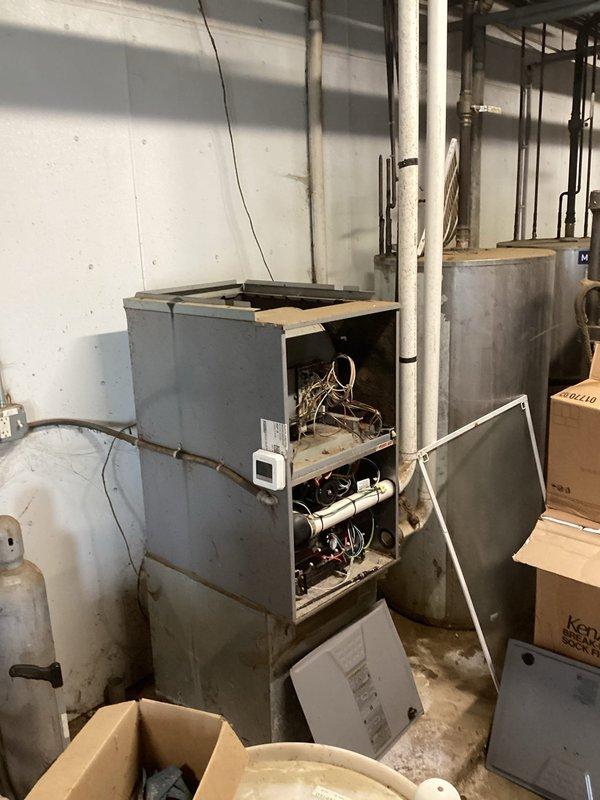Inspected inoperative furnace in dairy facility service room that had been unused since spring. Diagnostic examination revealed multiple critical failures: non-functioning blower motor, damaged blower wheel, and faulty control board. Documentation and photos were submitted for replacement estimate due to the extensive repairs needed and overall poor condition of the unit.