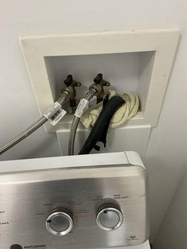 Completed installation of a toilet and shut-off valve in the master bathroom. Replaced failing supply line and emergency shut-off to prevent future damage. Documentation includes photos of the washing machine connection setup with water supply lines and the laundry area configuration.