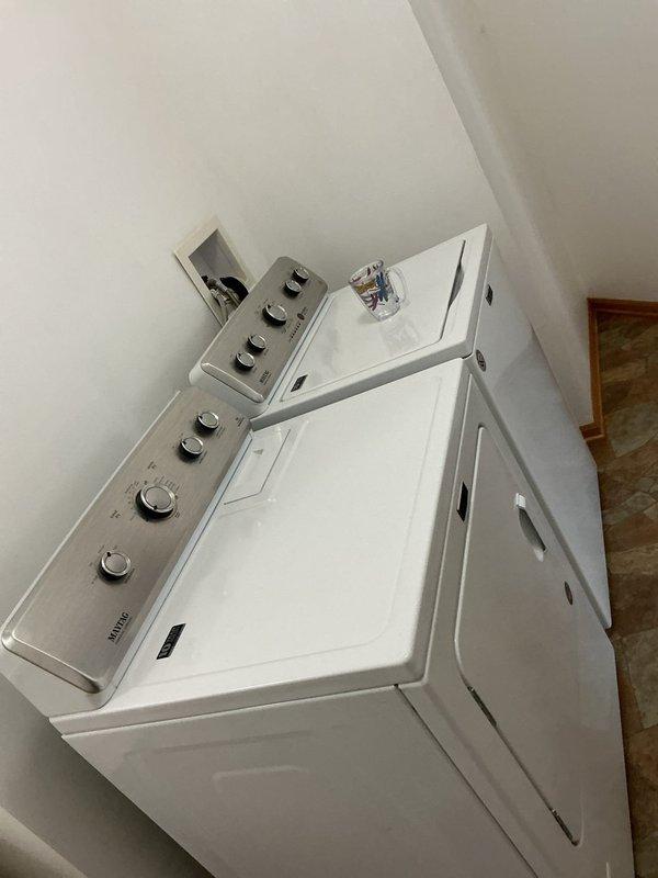 Completed installation of a toilet and shut-off valve in the master bathroom. Replaced failing supply line and emergency shut-off to prevent future damage. Documentation includes photos of the washing machine connection setup with water supply lines and the laundry area configuration.