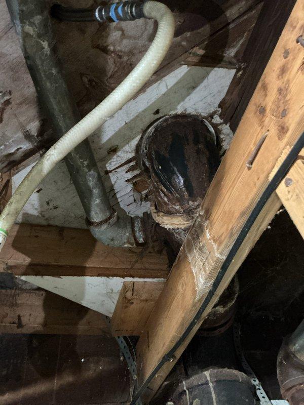 Performed inspection and evaluation of air admittance valve ("cheater vent") on vertical black vent pipe adjacent to laundry sink as flagged by inspector. Documented current installation with photos of utility area plumbing configuration while awaiting inspector determination on whether replacement is required or existing installation is permissible.