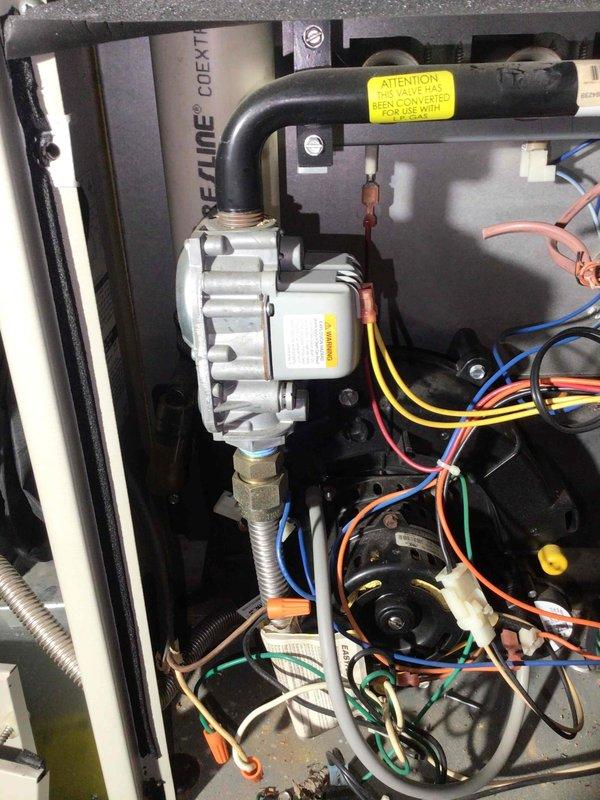 Responded to no heat call for 10-year-old system where customer reported unit would start then shut down. Upon inspection, identified gas valve showing visible smoke emission and electrical burning odor. Visual examination confirmed smoke coming from valve with no other apparent damage or over-voltage conditions. Customer was provided replacement options for the defective gas valve but declined service. Noted that system has been converted for propane use as indicated by warning label on valve assembly.
