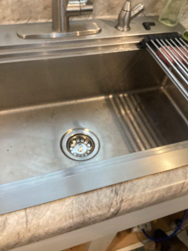 Removed faulty leaking garbage disposal from kitchen sink as requested by customer. Reconfigured plumbing with PVC P-trap assembly to establish standard drain connection. Installation includes new drain strainer basket in stainless steel sink, eliminating the disposal system entirely while maintaining proper drainage functionality.