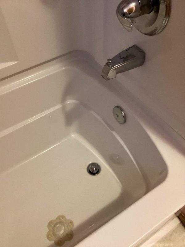 Responded to a callback for a recurring bathtub drain leak. Upon inspection, identified that the trap nut was cross-threaded, causing washer distortion and leaking during drainage. Removed trap nut and washer, then properly reinstalled components in correct orientation on threads. Performed testing to verify repair effectiveness with no leaks observed.