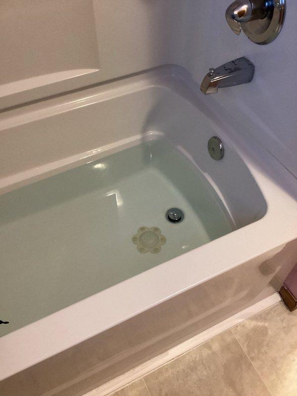 Responded to a callback for a recurring bathtub drain leak. Upon inspection, identified that the trap nut was cross-threaded, causing washer distortion and leaking during drainage. Removed trap nut and washer, then properly reinstalled components in correct orientation on threads. Performed testing to verify repair effectiveness with no leaks observed.