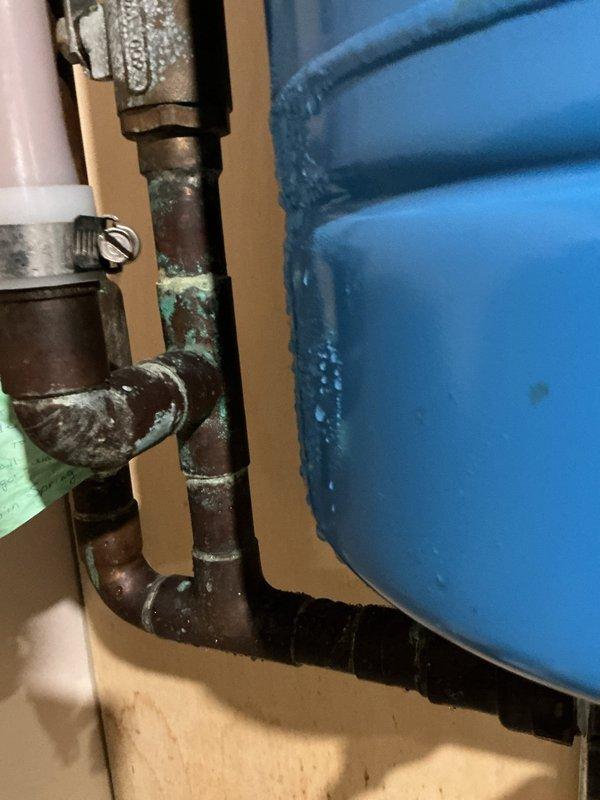 Located and repaired a leak in the copper piping connected to the Well-X-Trol pressure tank in the basement. Observed significant oxidation and corrosion at pipe joints, with visible water damage on the surrounding plywood wall indicating ongoing seepage. Completed repair of the compromised copper pipe section to resolve the issue.