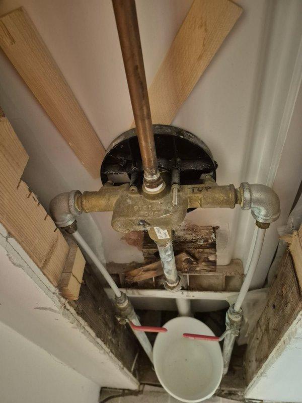 Diagnosed and repaired a leak in upstairs shower by replacing the damaged shower valve. Visual inspection revealed significant corrosion and mineral buildup on the existing valve assembly with evident water damage to surrounding wall structure. Installation of new shower valve successfully resolved the leak issue.