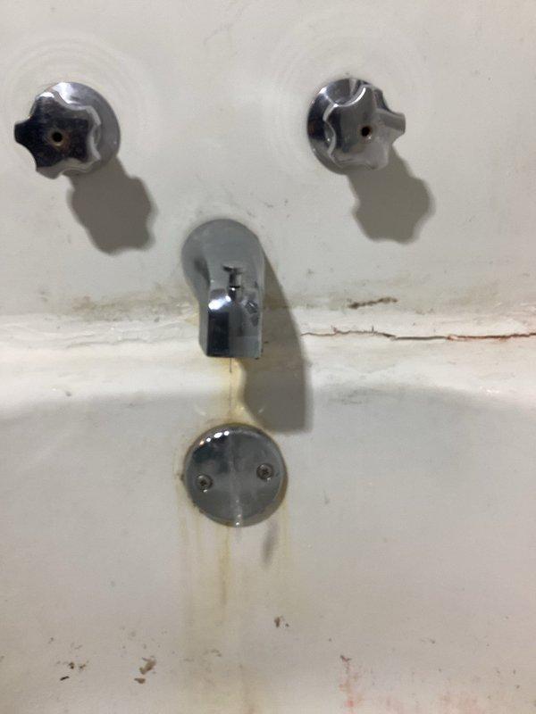 Diagnosed and replaced leaking two-handle tub faucet that was causing water to drip into basement. Removed old deteriorated fixture showing significant mineral buildup and porcelain cracking, and installed new faucet assembly to resolve the continuous drip issue.