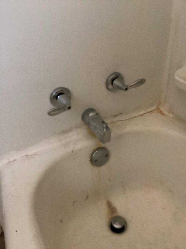 Diagnosed and replaced leaking two-handle tub faucet that was causing water to drip into basement. Removed old deteriorated fixture showing significant mineral buildup and porcelain cracking, and installed new faucet assembly to resolve the continuous drip issue.