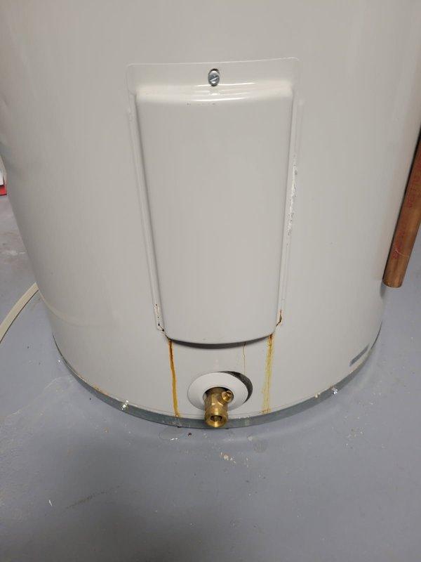 Replaced leaking 50-gallon Bradford White water heater showing significant rust and corrosion streaks from access panel to drain valve. New unit installed in utility area with proper copper and insulated pipe connections to existing plumbing system.