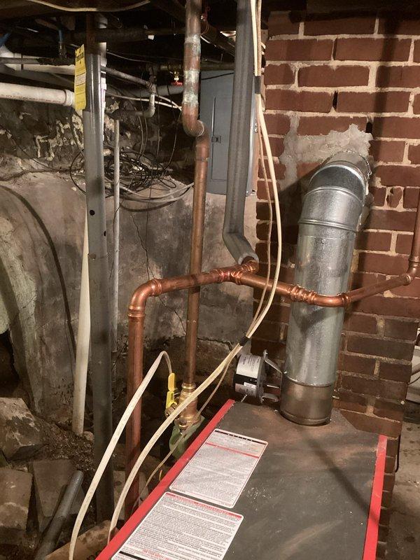 Responded to callback for no heat upstairs. Identified air lock in the system and resolved by bleeding significant air from purge valves where lines ascend to upper floor. Found and closed an incorrectly opened bypass valve which restored proper flow. System currently operational but noted several design issues including incorrectly piped expansion tank and questionable piping configuration. Recommended installation of conventional bladder tank with air scoop, auto fill, repipe on boiler return, and addition of glycol due to pipes running along exterior walls in this historic structure.