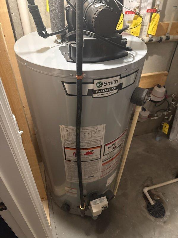 Replaced leaking, unrepairable water heater with new 50-gallon A.O. Smith ProLine XE natural gas power vent unit. Installation included proper connection of gas line, water lines, and PVC venting components in utility area with suitable drainage.
