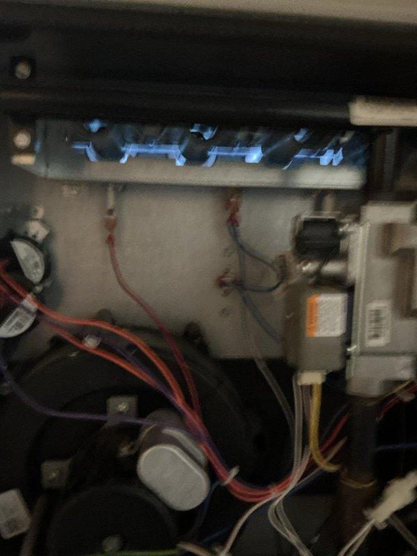 Diagnosed 11-year-old Tappan furnace with no heat condition despite thermostat indicating operation. Found reversed polarity code on initial inspection; after system reset, determined igniter had failed. Replaced igniter which restored proper ignition sequence as evidenced by normal blue flame pattern in burner assembly.