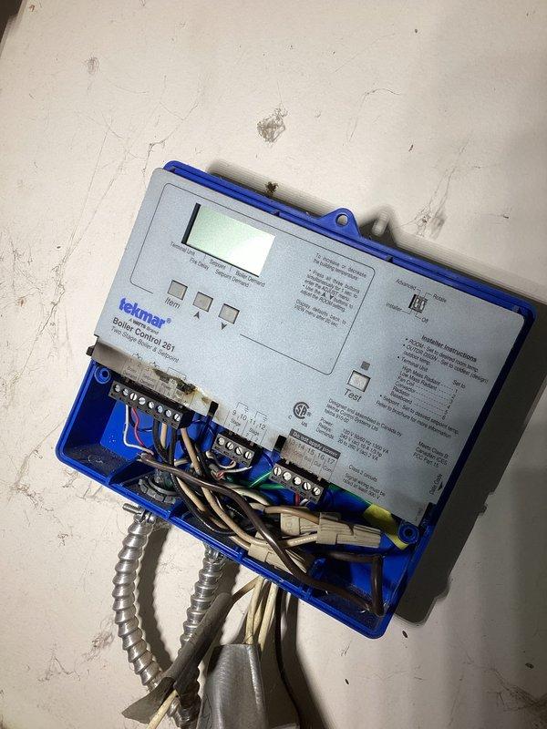 Diagnosed failed Tekmar control board in building 1400 boiler system that had caused complete heat loss to multiple apartments. Implemented temporary repair by installing two relays and a time delay circuit to bypass damaged board contacts, successfully restoring circulation pump operation and heat production. Set water pressure on both boilers to 20 PSI and ordered replacement control board for permanent repair during follow-up visit.