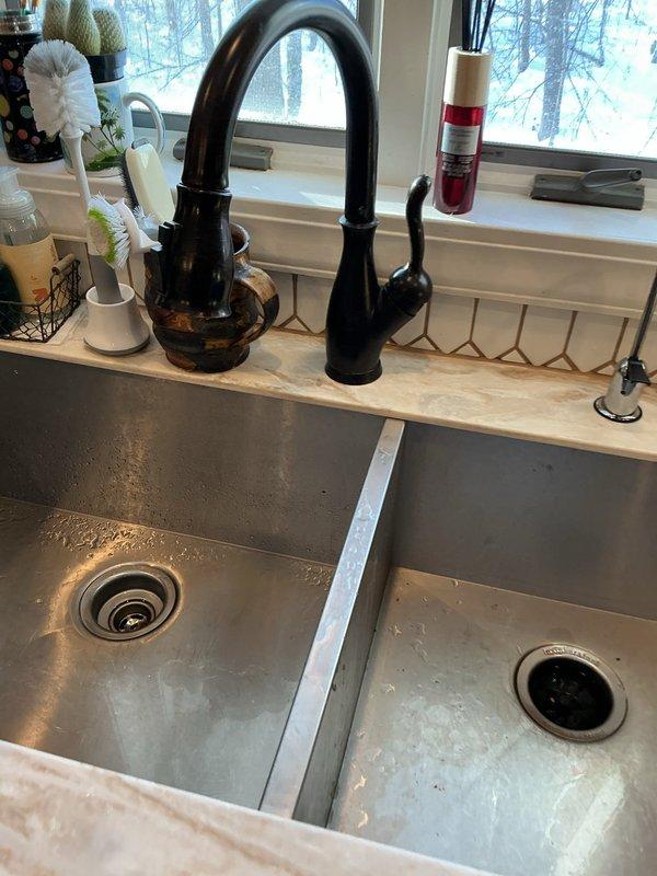 Responded to warranty service call for low water pressure issue at kitchen sink. Inspection revealed foreign plastic debris lodged in faucet head. Removed obstructive material from faucet aerator/head, restoring proper water flow and pressure to the kitchen sink.