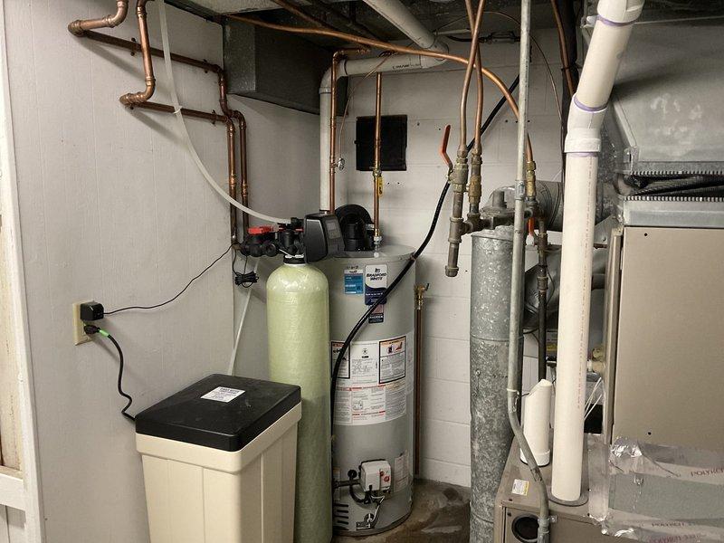 Relocated customer's water heater to improve access to furnace filter. Performed complete disconnection, draining, and repositioning of unit to leftmost possible position, then reconnected water supply lines and 2" PVC vent piping. All connections tested and verified operational.