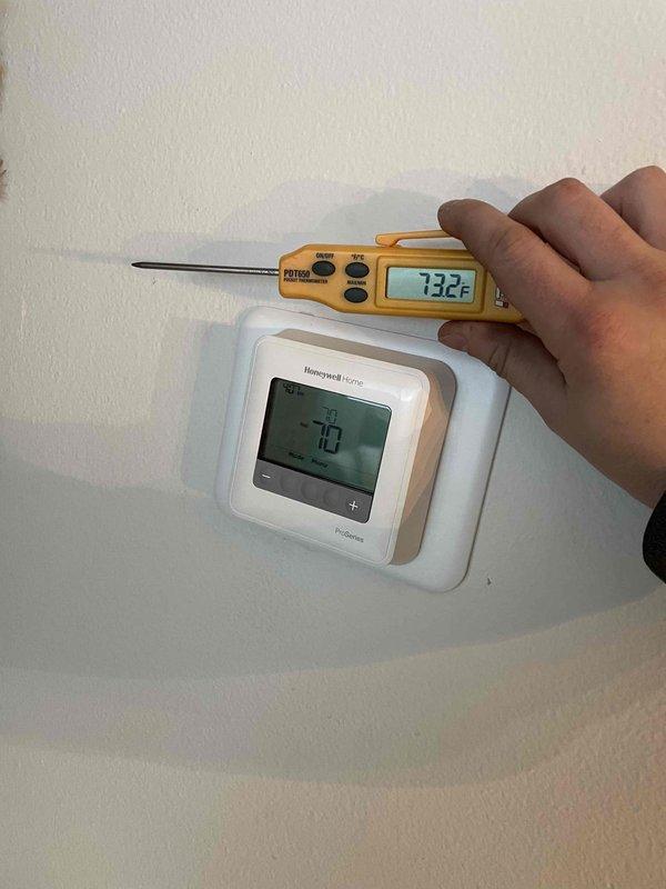 Diagnosed and resolved heating complaint by identifying thermostat was reading 3°F lower than actual room temperature due to cold air infiltration through wall penetration behind unit. Installed foam insulation behind thermostat to seal air leak, resulting in accurate temperature readings. Increased boiler maximum water temperature from 174°F to 182°F to improve heating capacity during extreme cold conditions.
