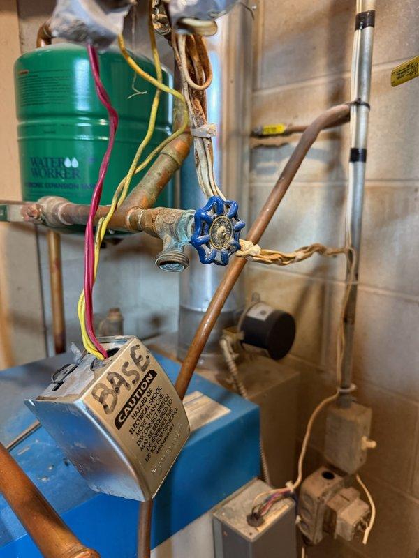 Responded to emergency call for overheating home. Diagnosed detached boiler stat and zone valve motor that had fallen off. Documented system condition with photos showing corrosion on copper piping and the disconnected valve components. Completed parts order form for replacement zone valve motor and advised customer of findings.