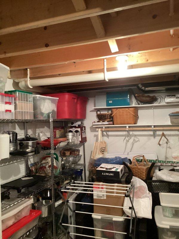 Responded to emergency service call for a leaking water heater system in utility room. Upon inspection, identified active leak from bottom of the tank with approximately 1/2 inch of standing water collected in drain pan. Documented existing configuration including expansion tank and associated copper piping connections. Recommended complete replacement of the failing unit.