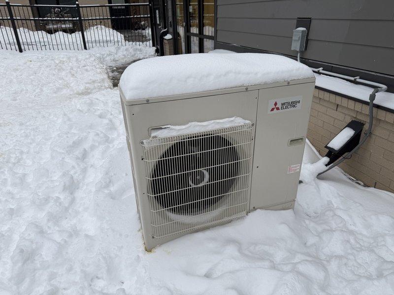 Responded to customer complaint of Mitsubishi mini split system not maintaining setpoint temperature (set at 72°F but only reaching 60°F). Upon inspection, found outdoor condensing unit completely buried in snow, preventing proper heat exchange and system operation. Cleared snow accumulation from unit and surrounding area to restore proper airflow. System tested after snow removal and confirmed fully operational with normal heating function restored.