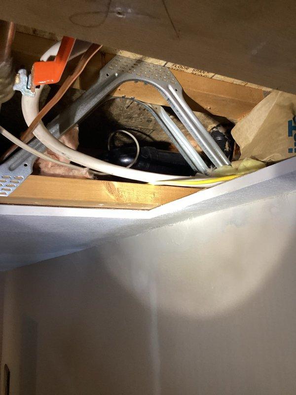 Responded to urgent service call for leaking ABS drain pipe located in wall behind lazy Susan and visible through ceiling. Accessed plumbing through ceiling access panels to diagnose issue. Identified source of leak in main drain line causing water damage to ceiling. Performed necessary repairs to compromised drain piping to resolve the active leak.