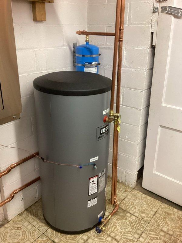 Diagnosed IBC boiler/water heater system experiencing inconsistent domestic hot water supply. Identified undersized boiler unable to meet demand requirements, failing circulator pump on domestic water side producing noise, and need for mixing valve installation. Documented system parameters via control panel showing DHW-indirect load configuration with 121°F tank setpoint, and recommended replacement of both boiler and pump along with mixing valve installation to resolve temperature fluctuations.