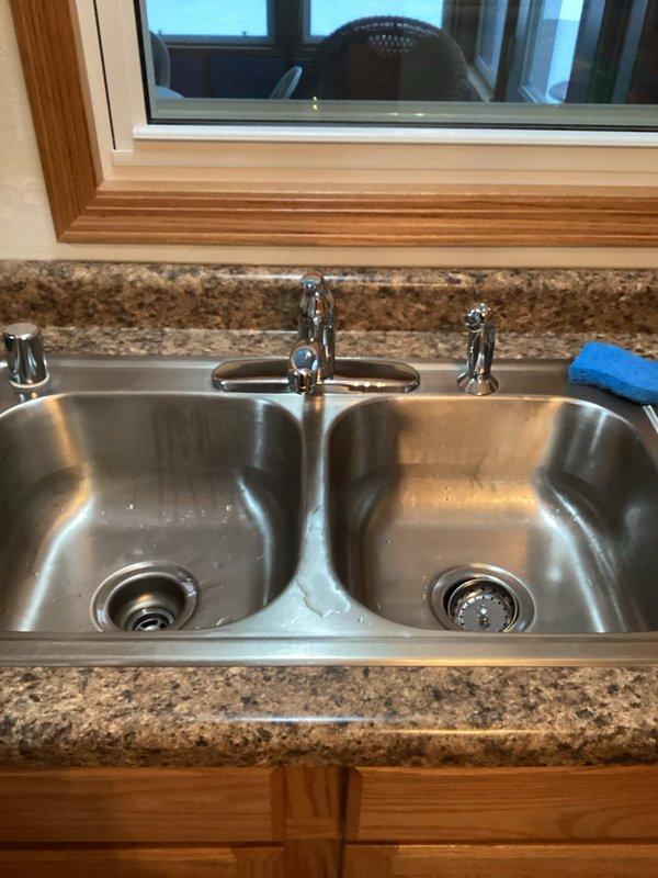 Installed homeowner-supplied kitchen faucet with side sprayer in double-basin stainless steel sink. Assessed basement toilet installation but determined customer's Tuscany model was incompatible with existing high flange; substituted with Gerber toilet for proper fit and function. Boxed customer's original toilet and placed in their vehicle.