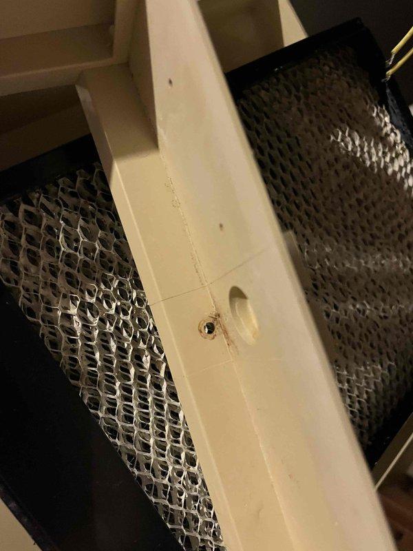 Responded to service call for previously repaired Aprilaire humidifier that had fallen again. Inspection revealed humidifier was improperly secured to the plenum with only tape rather than proper fasteners following previous system work. Observed pinched copper water line at saddle valve connection due to the fall. Documented condition with photos and recommended replacement of the damaged unit.