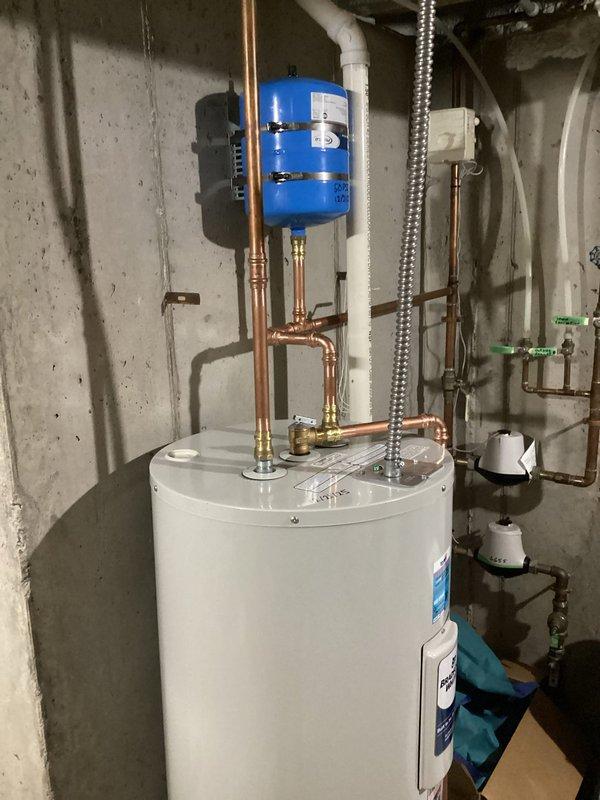 Replaced non-functioning electric water heater with a new 50-gallon Bradford White model after diagnosing a bad lower element and upper thermostat on the original 10-year-old unit. Installation included proper connection to existing copper piping and blue expansion tank mounted on the wall.