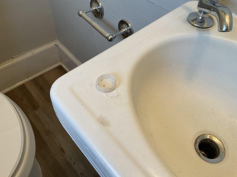 Diagnosed and resolved two bathroom sink issues: removed water bottle cap causing clog in main floor sink drain assembly, and replaced damaged components on second floor sink by installing new PVC sanitary tee, p-trap, and drain piping. Addressed leak-related ceiling damage likely caused by improper winterization of the home. Both sinks tested and confirmed fully operational after repairs.