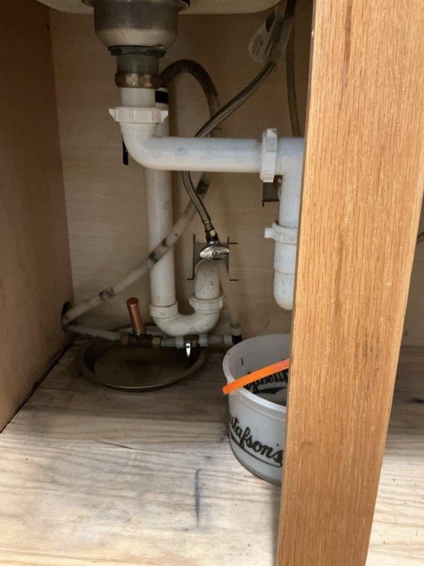 Responded to call for clogged kitchen sink experiencing slow drainage. Performed inspection of under-sink plumbing system, which showed white PVC pipes forming P-trap configuration with minor discoloration. Successfully cleared obstruction by running sewer machine through drain, restoring proper drainage function.