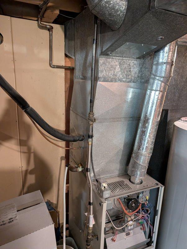 Responded to a no-heat service call on a 27-year-old Heil 80% furnace. Diagnosed failed thermostat that showed no display and was incorrectly activating AC. Inspection revealed all four burners had internal cracks, posing a safety hazard. Performed safety shutdown procedure and documented system condition with photos of the furnace installation and internal components.