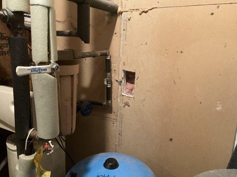 Replaced main house water valve and installed new water filtration housing in residential utility area. System includes blue pressure tank and beige sediment filter, with all connections properly secured and tested for functionality.