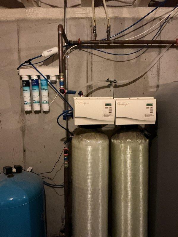 Responded to emergency water leak in basement mechanical room originating from kitchen sink. Discovered kitchen faucet head was coming apart causing significant leakage. Cleaned clogged drain in master bathroom sink and identified leaking tank T in basement water treatment system. Advised customer that tank T repair would require follow-up appointment.