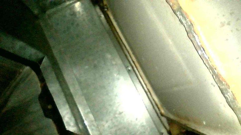 Responded to service call for a 16-year-old oil furnace exhibiting smoke at the injector and continuous fan operation. Inspection revealed improper ductwork modification with return air opening directly above the exhaust baffle, causing minor sooting. Heat exchanger was intact with no internal damage. Replaced nozzle, verified proper system function, and advised customer to relocate the return air opening further downstream and properly seal existing ductwork to prevent recurrence.