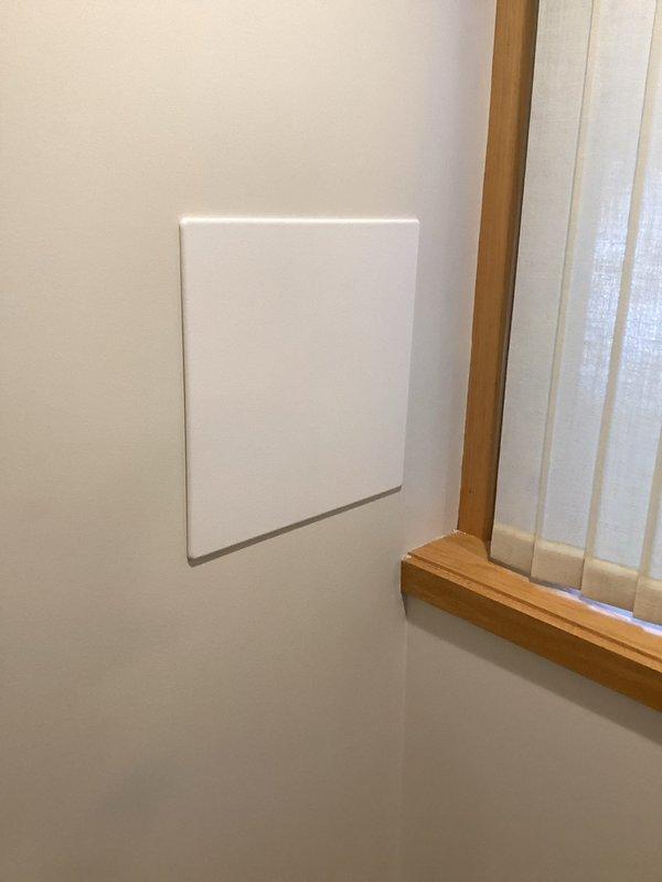 Accessed leaking hose bibb through interior wall cutout, revealing connection to primary plumbing system with pressure-treated support structure. Replaced faulty hose bibb and installed new white access panel for future maintenance, resolving leak that was penetrating wall.