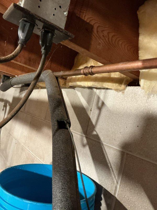 Repaired a pinhole leak in copper water softener supply line. Inspection revealed an approximate 8-12 pinhole perforation in the pipe. Applied appropriate repair method to seal the leak and verified water integrity. Protective bucket was placed below the affected area during repair process.