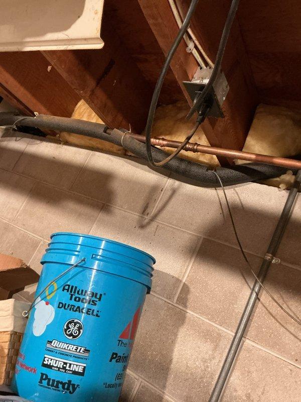 Repaired a pinhole leak in copper water softener supply line. Inspection revealed an approximate 8-12 pinhole perforation in the pipe. Applied appropriate repair method to seal the leak and verified water integrity. Protective bucket was placed below the affected area during repair process.