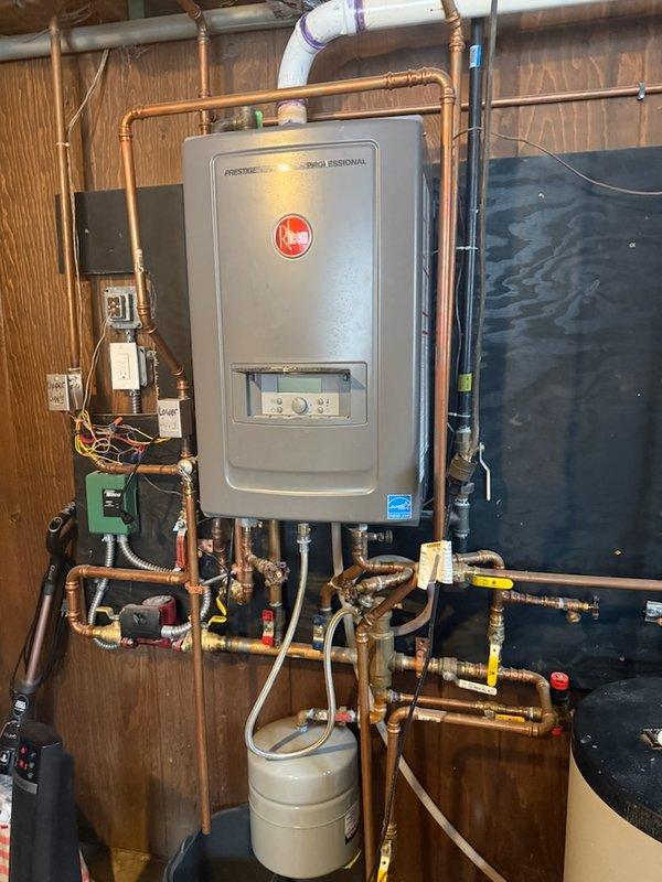 Conducted diagnostic inspection of residential water heating system with Rheem tankless water heater and customer-installed expansion tank. Identified active leak at T&P valve occurring upon water activation due to pressure issues. Also noted potential installation error where customer directed water into incorrect tankless heater inlet. Recommended transfer to HVAC technician with boiler expertise as system requires specialized repairs beyond standard plumbing scope.