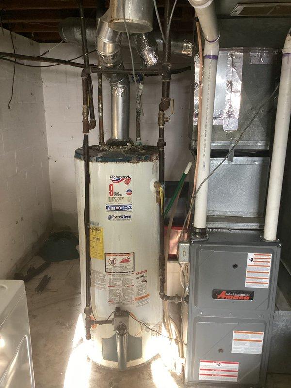 Performed inspection of two water heaters at Units A & B. First unit showed active leaking from top connections with significant corrosion and mineral buildup on copper pipes, moisture damage at base, and deterioration around floor connection points. Second unit (Richmond Integra model) appeared functional but was evaluated for replacement. Provided customer with replacement options and recommendations for both water heaters.