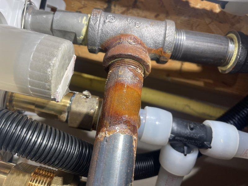 Responded to a no-heat service call for an older boiler system. Upon inspection, discovered a condensate cup that wasn't properly tightened, causing ongoing leakage since installation. Tightened the component to stop the active leak, cleaned the affected floor area, and noted some black organic growth on the back wall which customer acknowledged. Advised customer to periodically check the area for any future leakage issues.