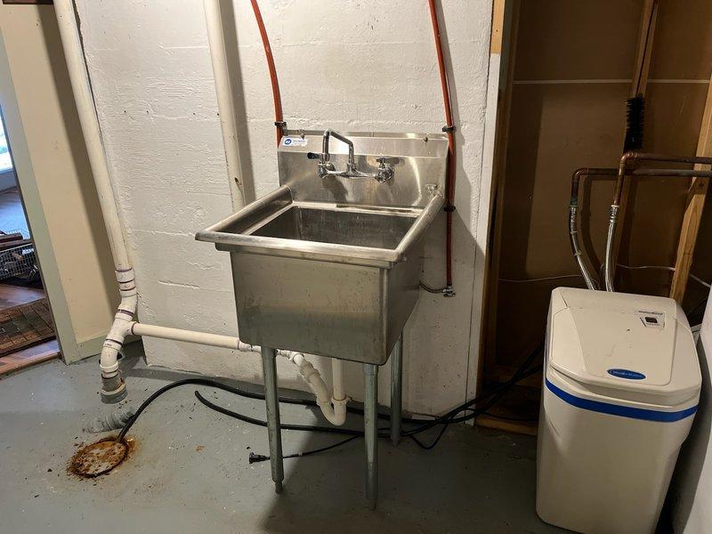 Successfully relocated utility laundry sink approximately 3 feet to accommodate customer's refrigerator and countertop installation. Reconfigured exposed PEX water lines, PVC drain, and vent piping to new location with proper connections. Verified functionality after installation with no leaks.