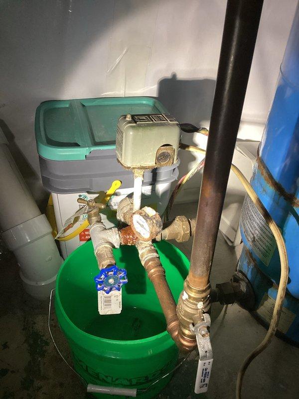 Technician responded to customer-reported leak near well pump system. Upon inspection, identified leak at the tank tee connection by pressure tank. Evaluated system components including copper piping, brass valves, and pressure gauge assembly. Provided estimate for tank tee replacement to resolve the active leak.