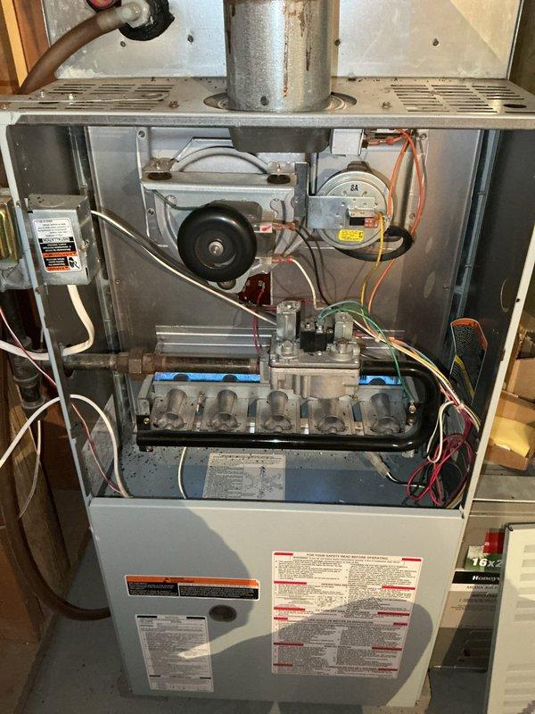 Diagnosed 26-year-old natural gas furnace that was cycling off after approximately 10 minutes of operation, causing complete power loss including thermostat blackouts. Inspection revealed a cracked heat exchanger adjacent to the high limit switch causing safety shutdowns, compounded by oil leakage from the blower motor and possible control board issues. Due to safety hazards and extensive component failures, determined unit was unsafe for continued operation and recommended complete system replacement.