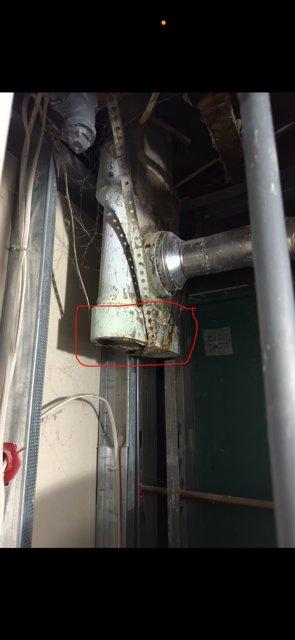 Inspected water heater flue system and identified significant corrosion and deterioration at the vertical vent pipe connection, resulting in water leakage from the flue. Documented the condition with photos showing the corroded metal joint and collected condensate. Submitted parts order for replacement tee fitting to restore proper venting integrity and prevent further moisture infiltration.